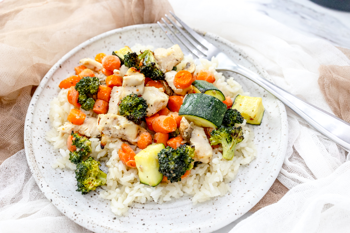 Air Fryer Chicken and Vegetables on a white plate with a silver fork on it.