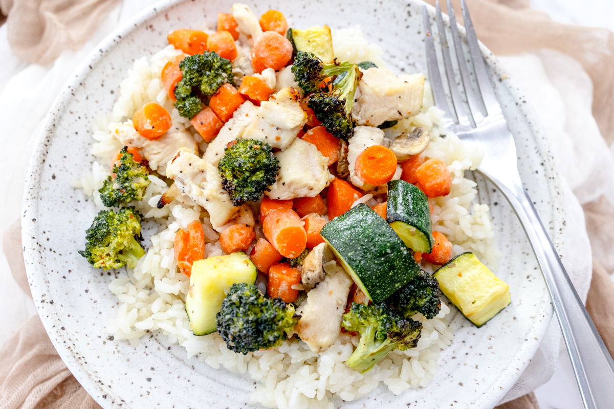 Air Fryer Chicken and Vegetables on a white plate with a silver fork on it.