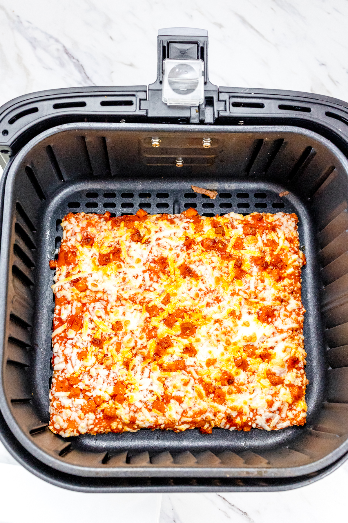 Totino's party pizza in an air fryer basket.